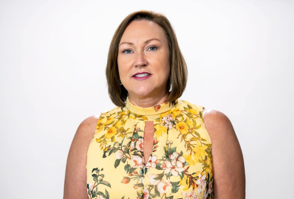 A headshot of Angie Sowell—a white woman with short brown hair, wearing a yellow floral blouse.