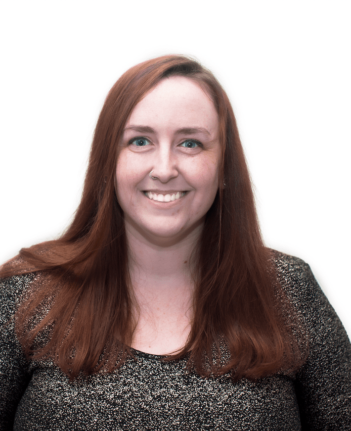 A headshot of Brea Giles—a younger woman with long brown hair, wearing a long-sleeved brown top,