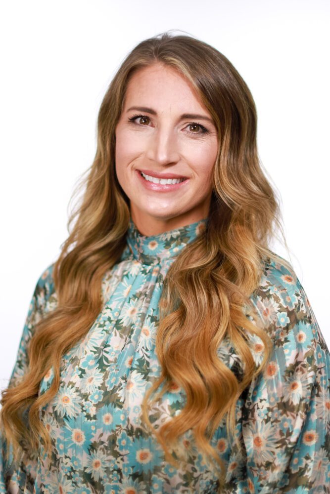 A headshot of Anna Knight—a woman with long, light-brown hair, wearing a floral print blouse.