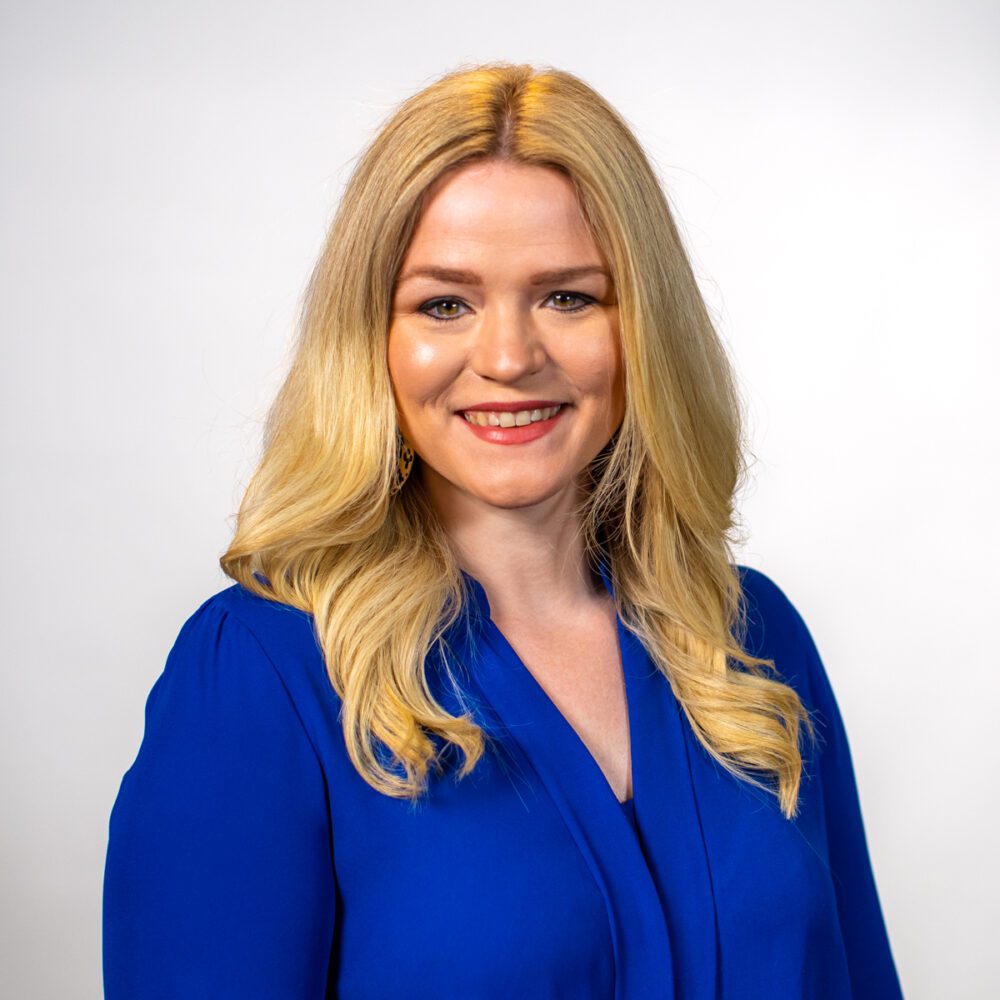 A headshot of Morgan Graham—A blonde woman wearing a bright blue blouse.